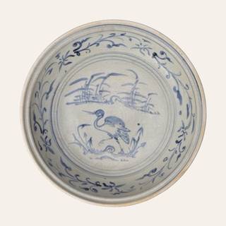 Large white‑glazed ceramic plate, painted in cobalt blue underglaze with graceful motifs of a stork among foliage